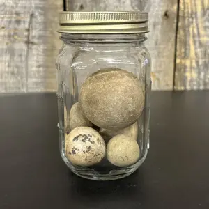 A Group of Five Spherical Stone Game Balls or Projectiles in a Glass Jar
