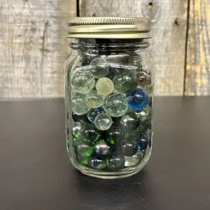 A Collection of Assorted Glass Marbles in a Clear Glass Utility Jar