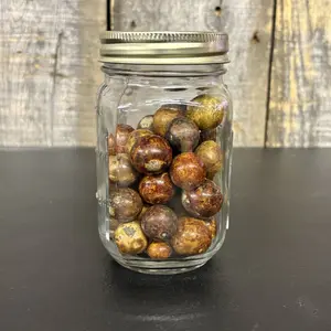 A Collection of Antique Glazed and Common Clay Marbles in a Graduated Glass Jar