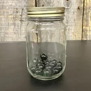 A Collection of Black Galaxy Glass Marbles in a Graduated Glass Jar