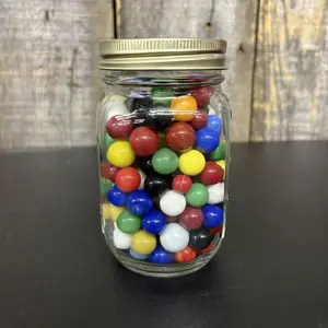 An Assortment of Glass Marbles in a Graduated Glass Storage Jar