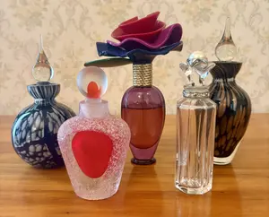 An Assortment of Five Decorative Art Glass and Designer Perfume Bottles