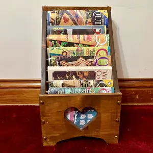 A Collection of Quilting Periodicals and Books in a Wooden Heart Magazine Rack